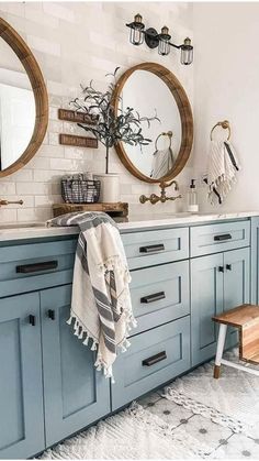 a bathroom with blue cabinets and two round mirrors