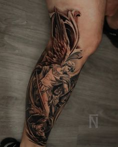 a man's arm with an angel and demon tattoo on the left side of his leg