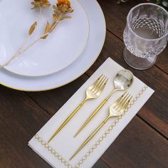 gold colored forks and spoons sitting on a white plate