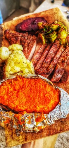 a person holding a plate with meat and vegetables on it