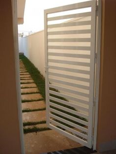 an open white door leading to a small yard with grass growing on the side walk