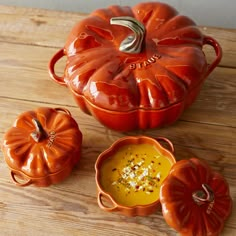 an orange pumpkin shaped dish with two small dishes next to it on a wooden table