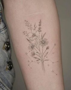 a woman's arm with flowers and stars tattooed on the back of her body