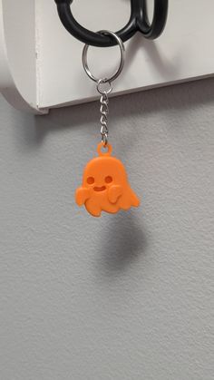 an orange keychain hanging from the side of a white hook on a gray wall