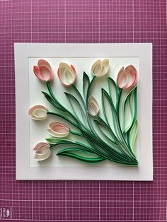 paper flowers are arranged on top of a piece of white and green paper, with pink squares in the background