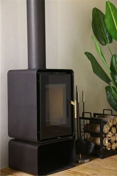 a black stove sitting on top of a wooden table next to a potted plant