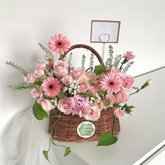 a basket filled with pink flowers sitting on top of a white counter next to a mirror