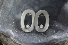 These earrings are handmade from recycled 14k white gold. Each earring contains one .15ct G color SI1 clarity diamond. Together, these earrings weigh 4.4 grams. The posts are 14k white gold and come with 14k white gold friction backs. Each earring measures 22.5mm (14.5/16 inch) in long and 9.8mm (9.5/16 inch) wide. These earrings are a modern and classy design that can be dressed up or down for any occasion. Available in brushed or high polish, please indicate at checkout. Modern Oval Diamond Earrings With Prong Setting, Modern Round Earrings With Single Diamond, Modern Oval Brilliant Cut Diamond Earrings, Modern Brilliant Cut Oval Diamond Earrings, Modern Oval Brilliant Cut Earrings, Oval White Gold Earrings With Single Cut Diamonds, Modern Sterling Silver Diamond Earrings For Everyday, Modern Oval White Gold Earrings, Oval Single Diamond Earrings In Fine Jewelry Style