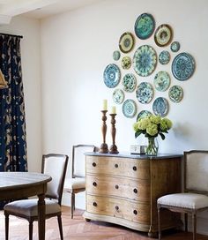 a dining room table and chairs with plates on the wall