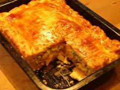 a casserole dish on a wooden table with one piece missing from it's crust