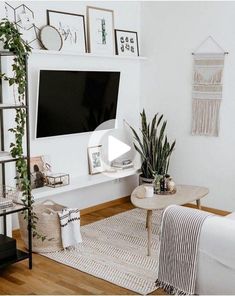 a living room with white furniture and a flat screen tv mounted on the wall above it