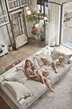 a woman sitting on top of a couch next to a child in a living room