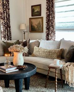 a living room filled with lots of furniture next to a window covered in drapes