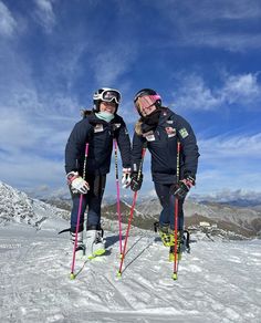 two people on skis standing in the snow with their ski poles and goggles