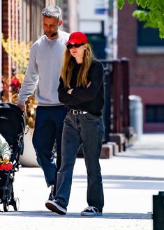 a man and woman walking down the street with a baby in a stroller