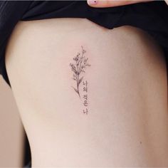 the back of a woman's thigh with a small flower tattoo on her left side