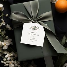 a present wrapped in green paper and tied with a ribbon next to some white flowers