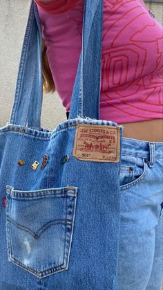 a woman holding a blue jean purse with patches on it's sides and the bottom part of her stomach