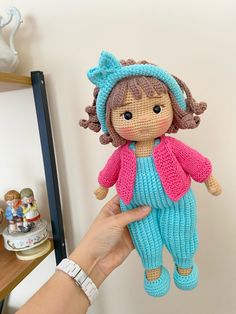 a hand holding up a knitted doll