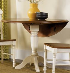 a dining room table with two chairs and a vase on top of it, in front of a window