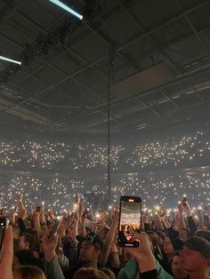 a group of people holding up cell phones in front of an audience at a concert