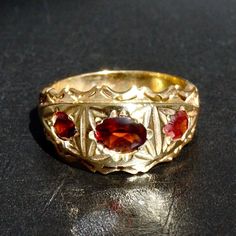 Capture a beautiful moment with this 18K Yellow Gold Plated Silver Garnet three-stone Band Ring. Handmade with natural gemstones, this unique jewelry is a daring addition to your collection. Size 10.25, but can be resized - go bold and add a special sparkle! METAL : .925 Sterling Silver + gold plated STONE: natural Garnet SIZE: US 10.25 *for other sizes pease leave a message after order. Antique Gemstone Signet Ring For Anniversary, Antique Gold Three-stone Jewelry, Antique Three Stone Gold Jewelry, Gold Ruby Ring With Three Stones, Oval Shaped, Gold Oval Ruby Ring With Three Stones, Three Stone Garnet Jewelry For Anniversary, Yellow Gold Multi-stone Signet Ring Gift, Heirloom Gemstone Signet Ring For Anniversary, Antique Three Stone 14k Gold Jewelry