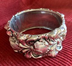 This is a gorgeous unsigned hinged or clamper bracelet, most likely by Whiting and Davis.  While unmarked, it is believed to be Whiting and Davis because when this bracelet was sold as part of an earring/bracelet set, the bracelets did not carry the Whiting and Davis mark.  It has a striking and ornate repousse art nouveau design and is a big, bold bracelet at 1 1/4" wide while also bringing a delicate touch at the same time with the beautiful design.  This bracelet is sure to bring that special touch to any summer outfit!  A statement bracelet also makes a perfect gift and its timeless style will appeal to so many!  The bracelet has a push-in clasp but it is missing the safety chain.  There is a place for it;  you could easily take it to a jeweler or purchase one and attach it yourself. Vintage Cuff Bracelet With 17 Jewels For Formal Occasions, Unique Engraved Bangle For Formal Occasions, Antique Hinged Bracelet For Formal Occasions, Antique Hinged Bracelets For Formal Occasions, Antique Bracelet For Evening Wear, Formal Hinged Bracelet Jewelry, Vintage Hinged Bangle For Formal Occasions, Vintage Metal Cuff Bracelet For Formal Occasions, Antique Hinged Cuff Bracelet For Formal Occasions