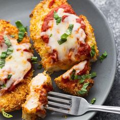 two pieces of chicken parmesan on a plate with a fork