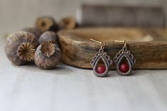 a pair of earrings sitting on top of a piece of wood next to some mushrooms