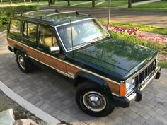 a green and brown jeep parked in front of flowers