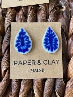 two blue and white earrings sitting on top of a piece of paper