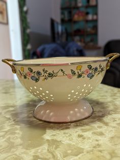 a white bowl with flowers on it sitting on a table