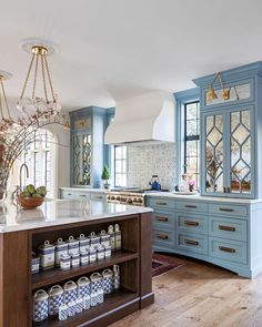 a large kitchen with blue cabinets and white counter tops, an island in the middle