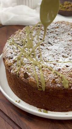 a cake on a white plate with green icing being drizzled over it