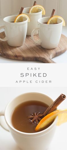 three cups of apple cider with cinnamon and an orange slice on the side, in front of two white mugs