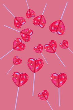 several lollipops shaped like hearts on pink background