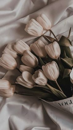 a bouquet of white tulips laying on top of a bed