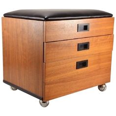 a wooden cabinet with two drawers and black leather top on casteors, against a white background