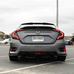 the rear end of a gray car parked in a parking lot