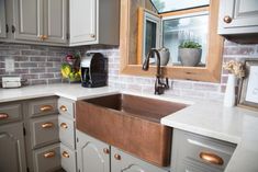 a kitchen sink sitting under a window next to a counter