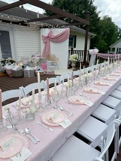 a long table set up with pink and white place settings