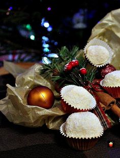 some cupcakes wrapped in brown paper and decorated with christmas decorations on a table