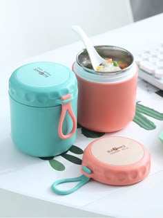 the lunch box is sitting on the table next to the keyboard and cup with spoon in it