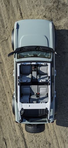 an overhead view of the back end of a truck with its doors open on dirt ground