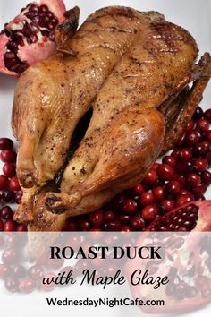 roast duck with maple glaze on a white plate surrounded by cranberries and pomegranates