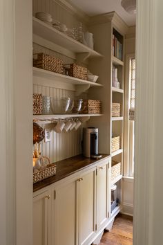 a kitchen with white cabinets and shelves filled with plates, bowls and cups on top of them