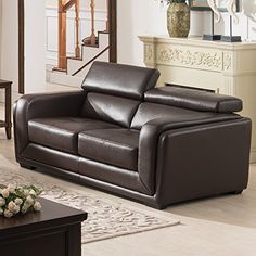 a brown leather couch sitting in a living room next to a coffee table and stairs