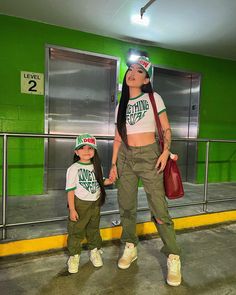 a woman and child standing in front of a green wall