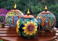 three colorfully painted vases with lit candles in them sitting on a wooden table