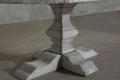 an old table with two wooden legs and some wood planks on the top, sitting in a concrete room